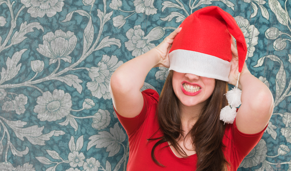 angry woman with a christmas hat covering her eyes against a vintage background